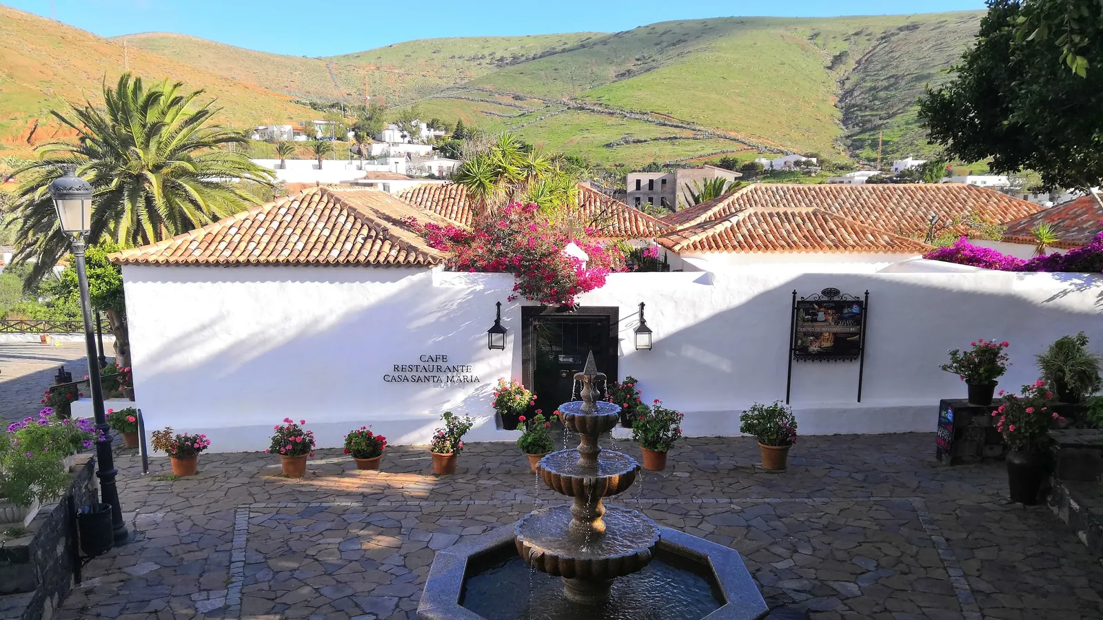 White houses of Betancuria with a stone fountain and pink bougainvillea