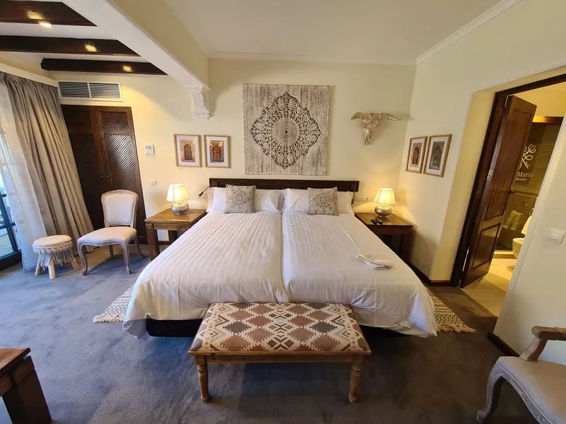 Double Room Nº 2: the bed with a carved ornament above it and a patterned bench at its foot