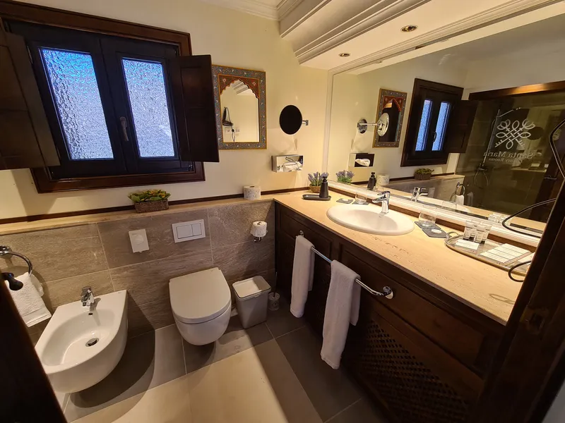The bathroom with a washbasin, a mirror and a shuttered window