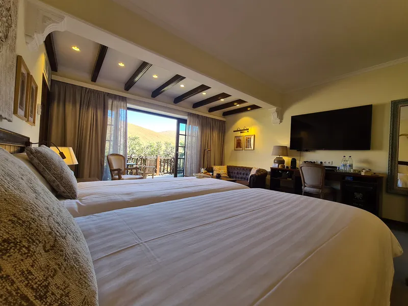 Double Room Nº 3: the beds, a sofa corner and the terrace doors open to the mountains