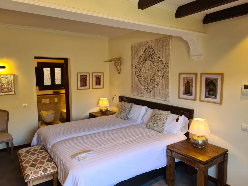 The beds beneath a carved ornament, with a patterned bench