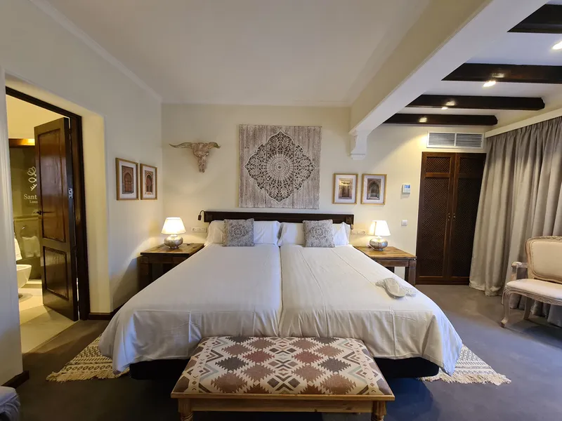 The beds with a patterned bench and the door to the bathroom