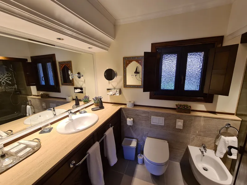 The bathroom with two washbasins, a mirror and a shuttered window