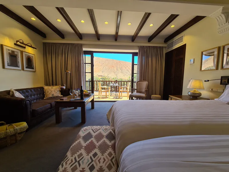 Double Room Nº 4: the bed, a leather sofa and glass doors open to the terrace and the mountains