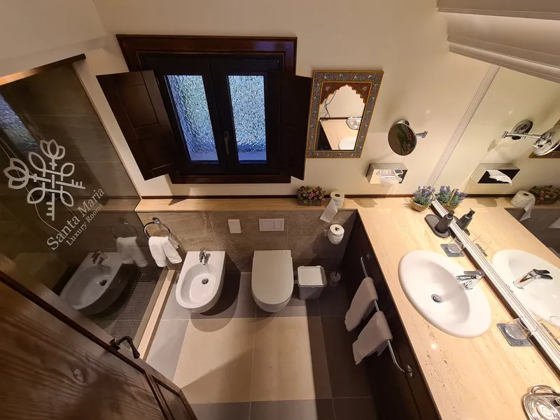 The bathroom with two washbasins, a shower and a shuttered window