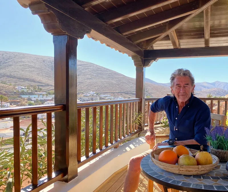A man at the table on the covered balcony, with a bowl of oranges