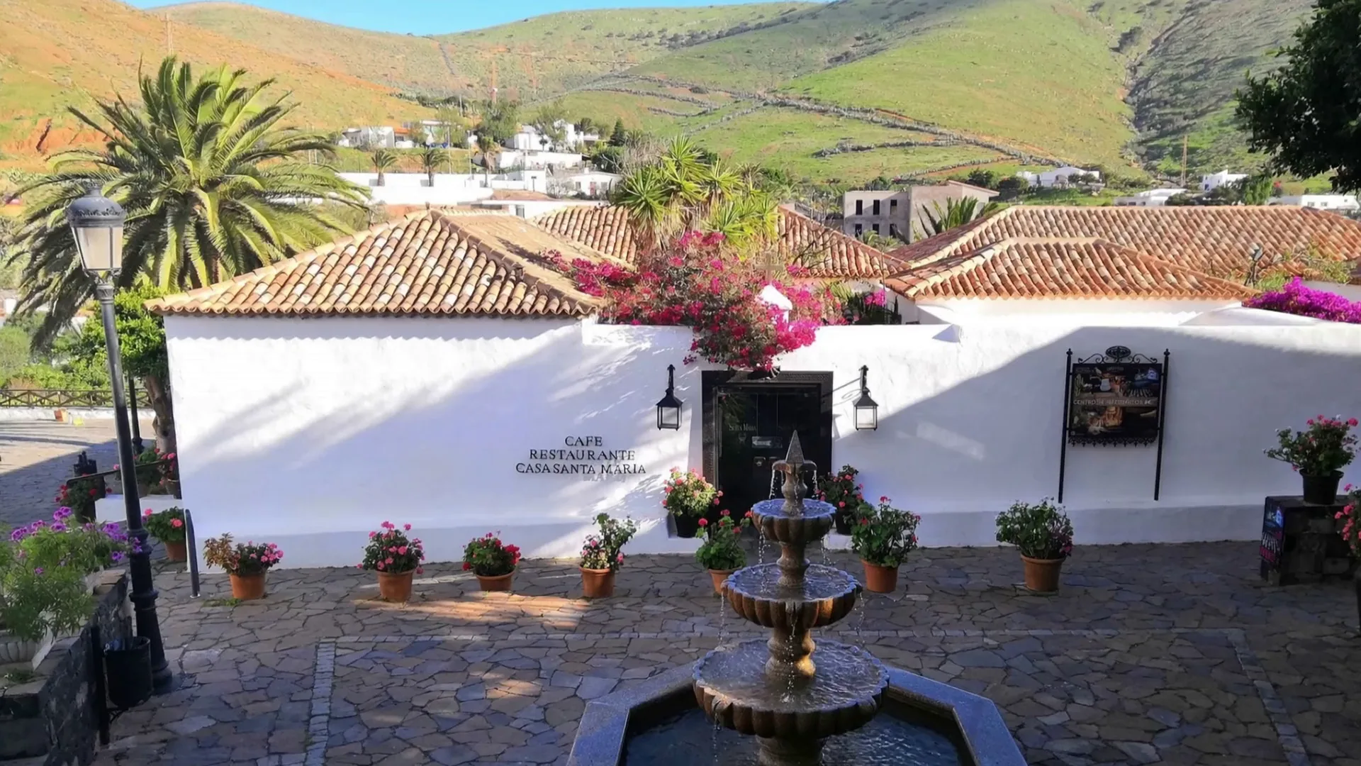 White houses of Betancuria with a stone fountain and pink bougainvillea
