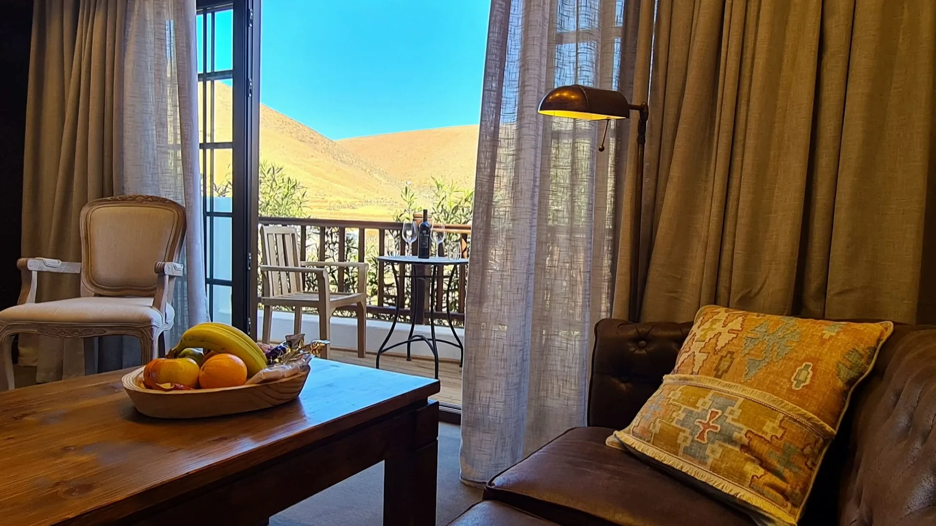 Double Room Nº 3: the terrace door open to the mountain, a bowl of fruit on the table and a leather sofa in front